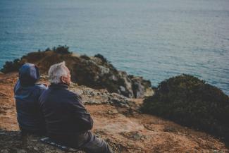 two person sitting on rock staring at body of water during daytime by Katarzyna Grabowska courtesy of Unsplash.