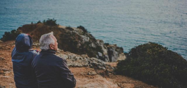 two person sitting on rock staring at body of water during daytime by Katarzyna Grabowska courtesy of Unsplash.